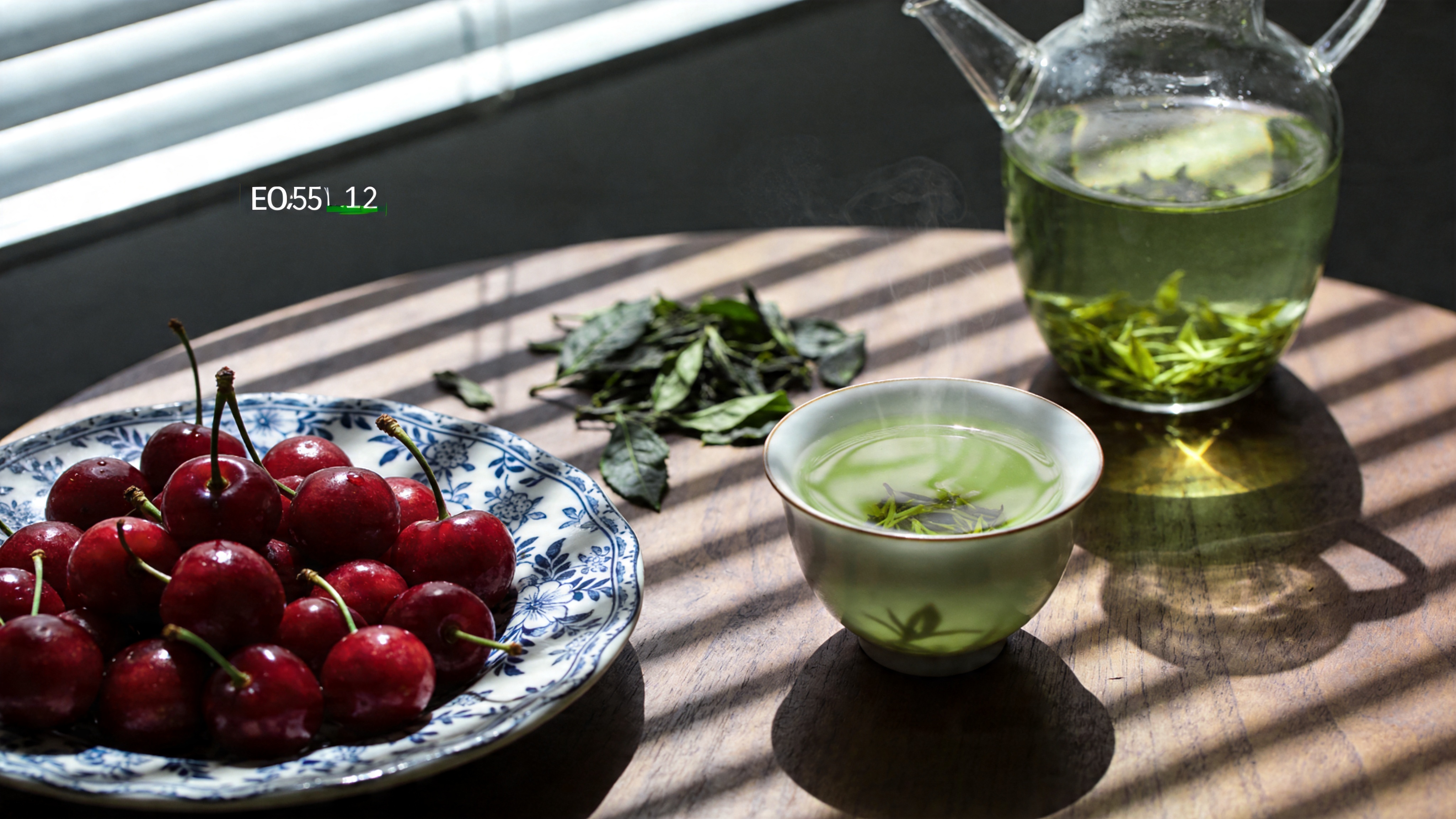 一幅极具质感的超写实静物摄影特写。背景是虚化的深灰色调，聚焦于一张古朴的胡桃木圆桌。桌上摆放着一只精致的青花瓷盘，盘中盛着几颗鲜红欲滴的樱桃，樱桃表面光滑如镜，映照着窗外的倒影。旁边放着一杯刚冲泡好的碧螺春绿茶，热气袅袅升起，茶汤清澈嫩绿。一只透明的玻璃水壶旁，随意地散落着几片刚采摘的新鲜茶叶，叶脉清晰可见。阳光从侧上方的百叶窗缝隙中斜射进来，在樱桃和茶杯上投下清晰锐利的光影，强调出春日午后的慵懒与惬意。

专业商业摄影风格，佳能EOS R5拍摄，85mm f/1.2镜头。极致的景深控制，主体锐度极高，边缘柔和。色彩还原真实自然，略带低饱和度的高级感。光影细腻，强调材质的对比（瓷器的温润、玻璃的通透、水果的蜡质、木纹的粗糙）。画面构图严谨，具有生活美学杂志的质感。